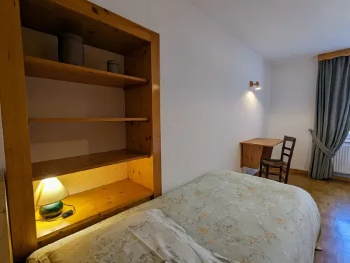 Interior de habitación de madera con nichos de almacenamiento, cama y escritorio.