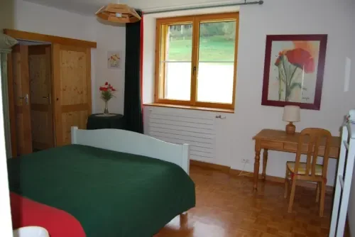 Habitación con ropa de cama verde, muebles de madera y vistas al jardín.