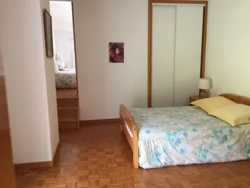 Habitación espaciosa con cama de madera y suelo de parquet.