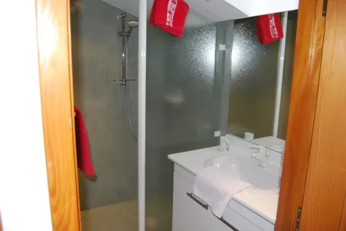 Baño de la habitación con lavabo blanco y ducha a ras de suelo.