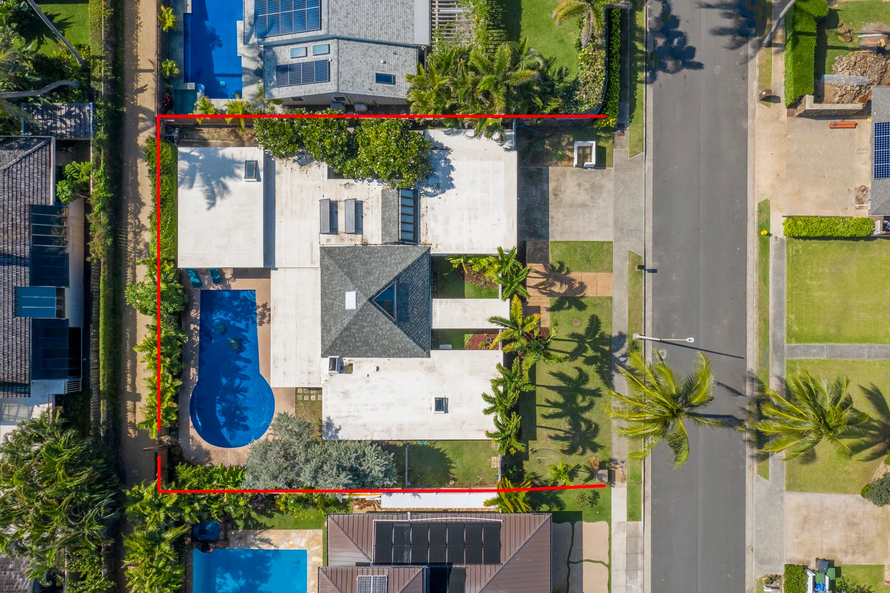 Una vista aérea muestra una casa, una piscina azul y la calle circundante.