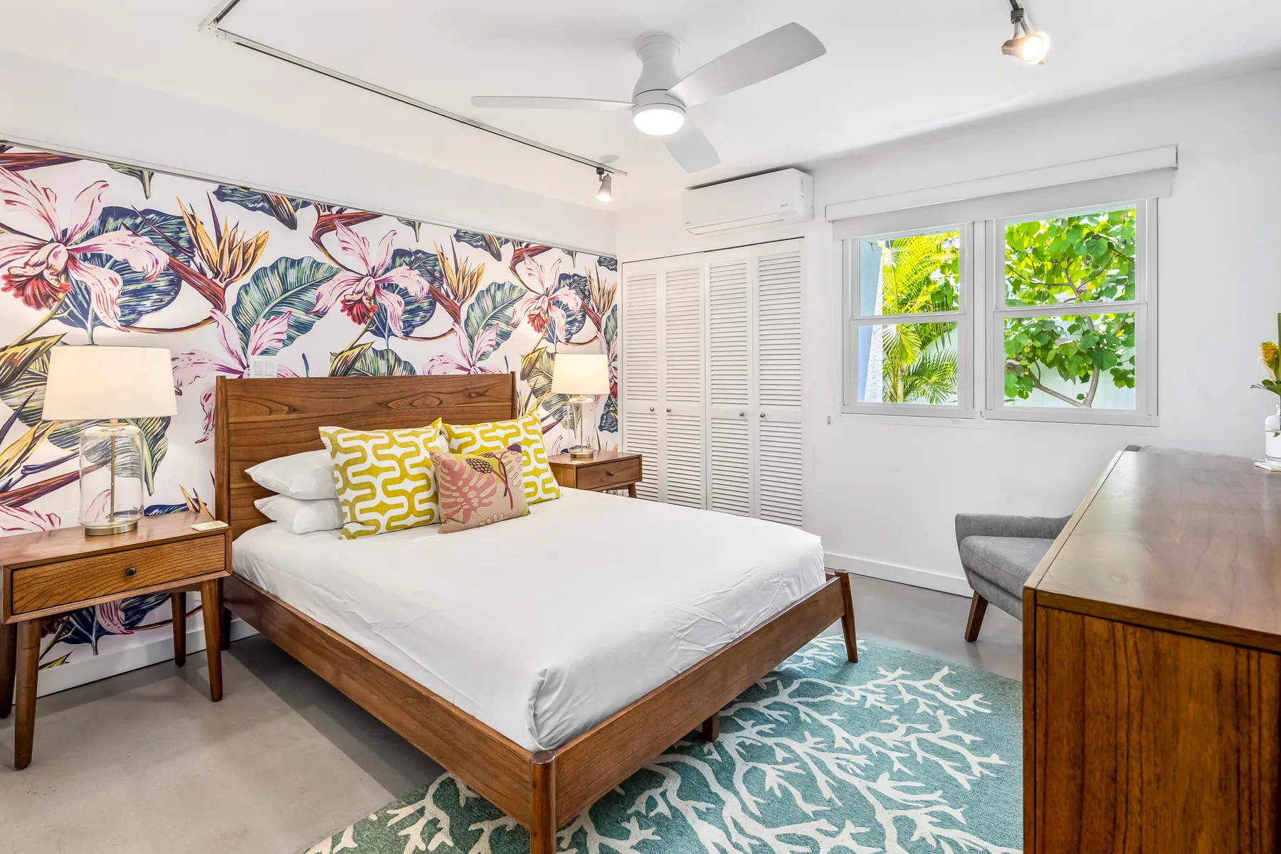 Un dormitorio con una cama de madera, una pared floral y una ventana con vegetación.
