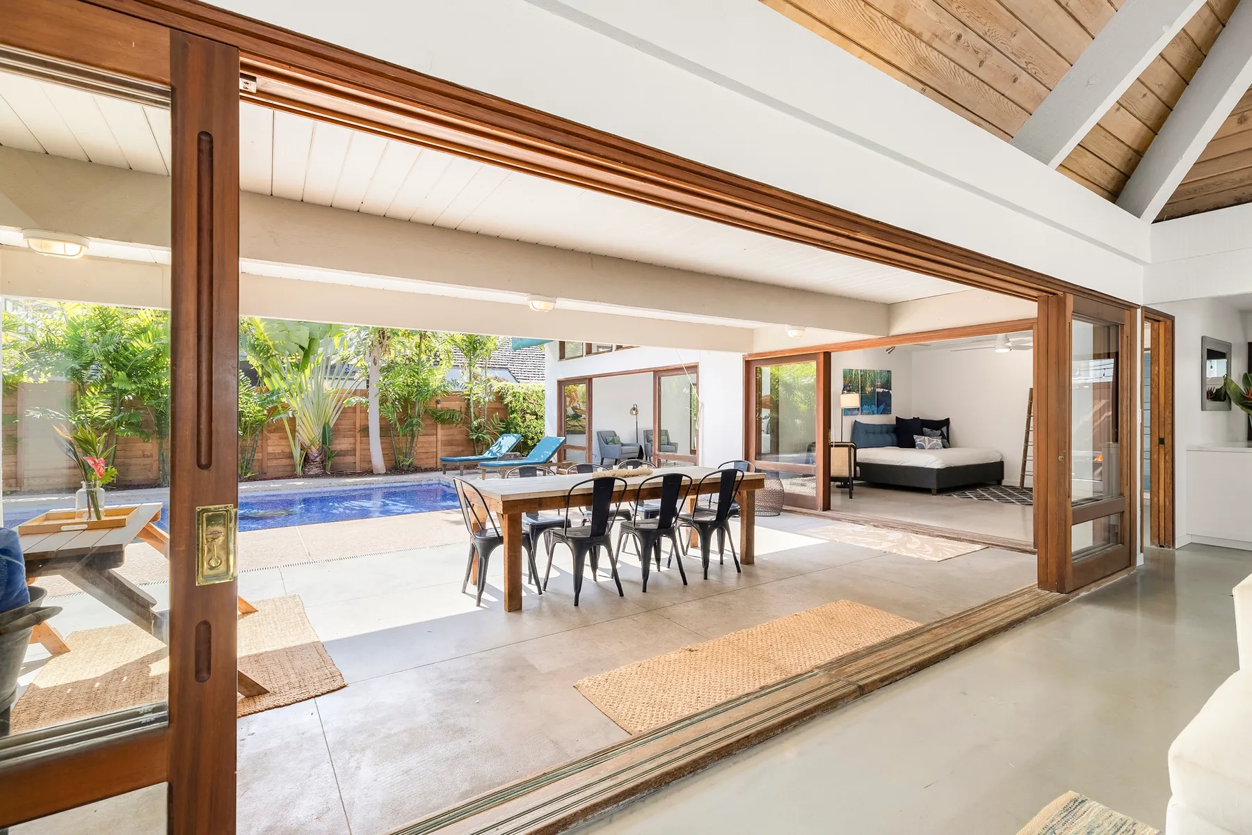 Una zona abierta de comedor y estar da a una piscina a través de amplias puertas corredizas de vidrio.