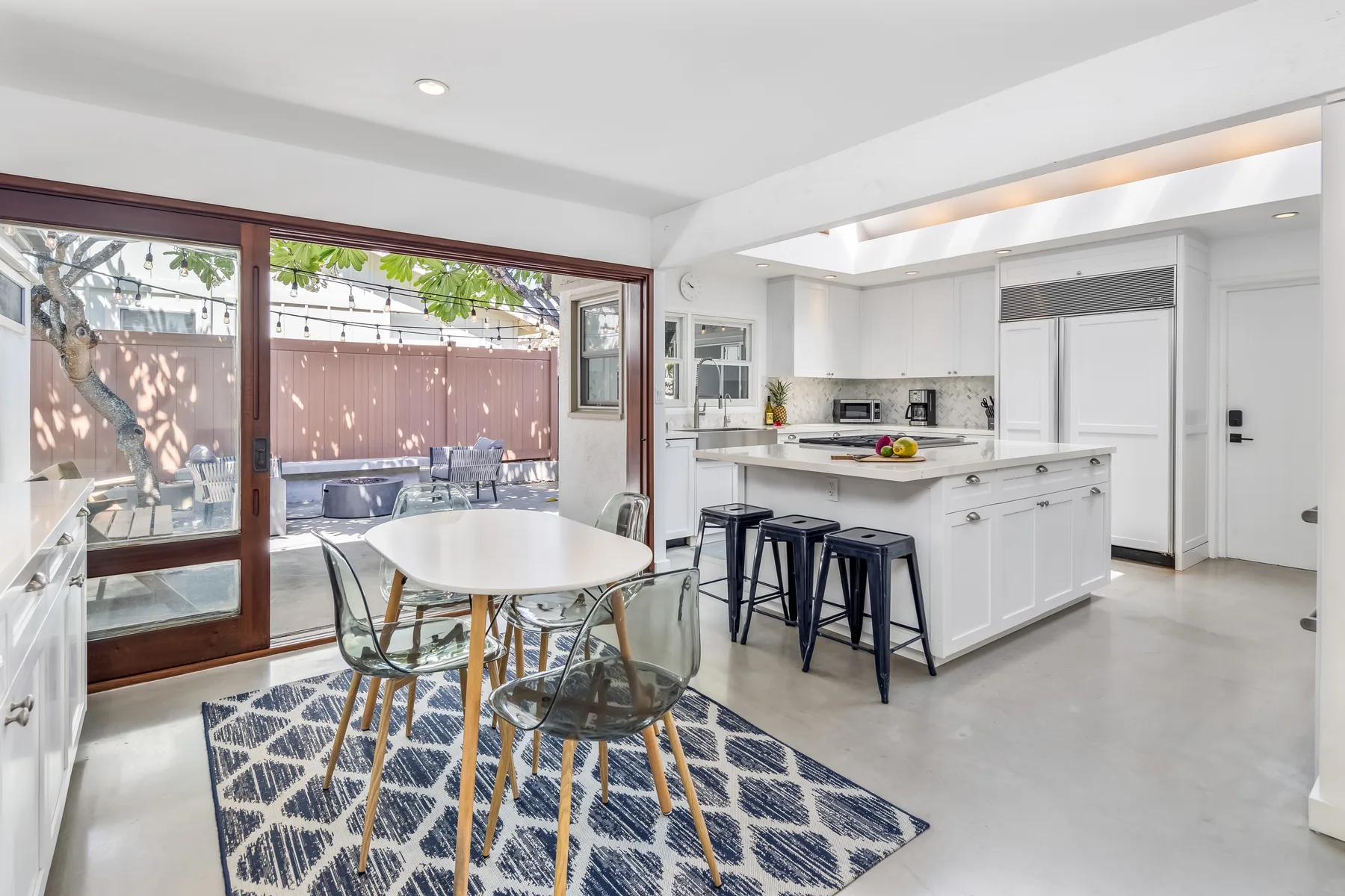 Una cocina luminosa con comedor se abre a un patio mediante grandes puertas de vidrio.