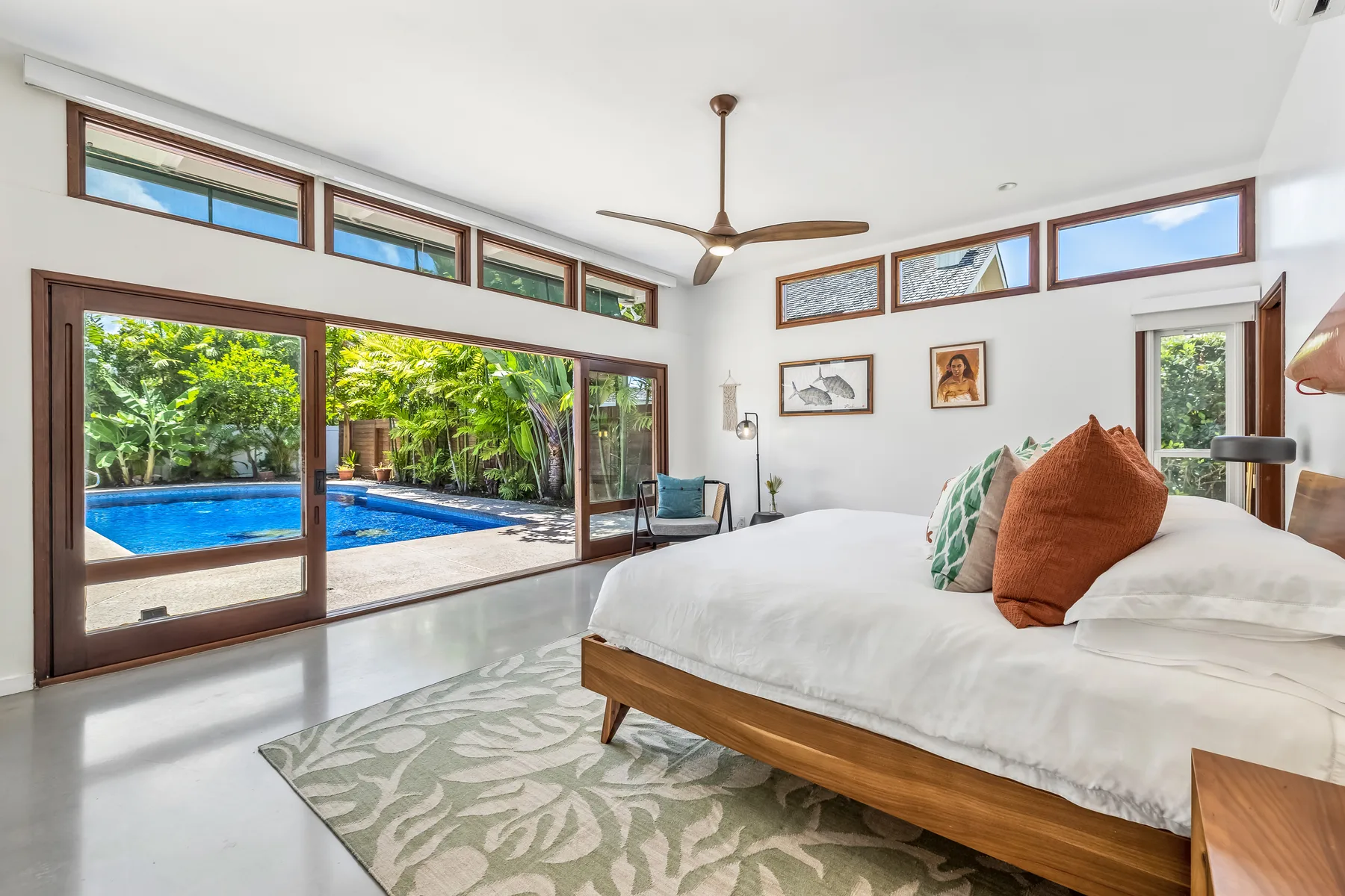 Un dormitorio luminoso con una cama grande y puertas corredizas de vidrio hacia la piscina.