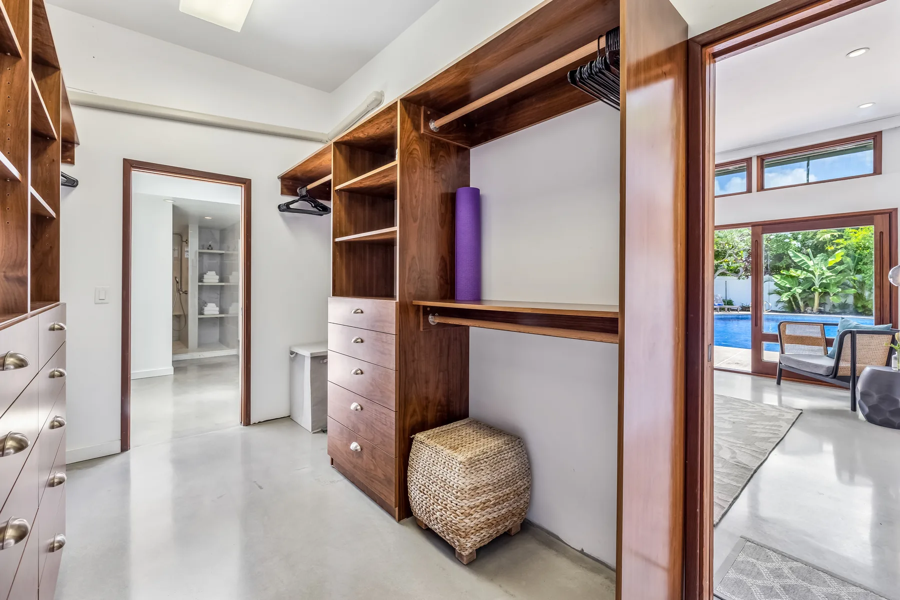 Un vestidor con estantes de madera y una puerta que da a una luminosa sala de estar.