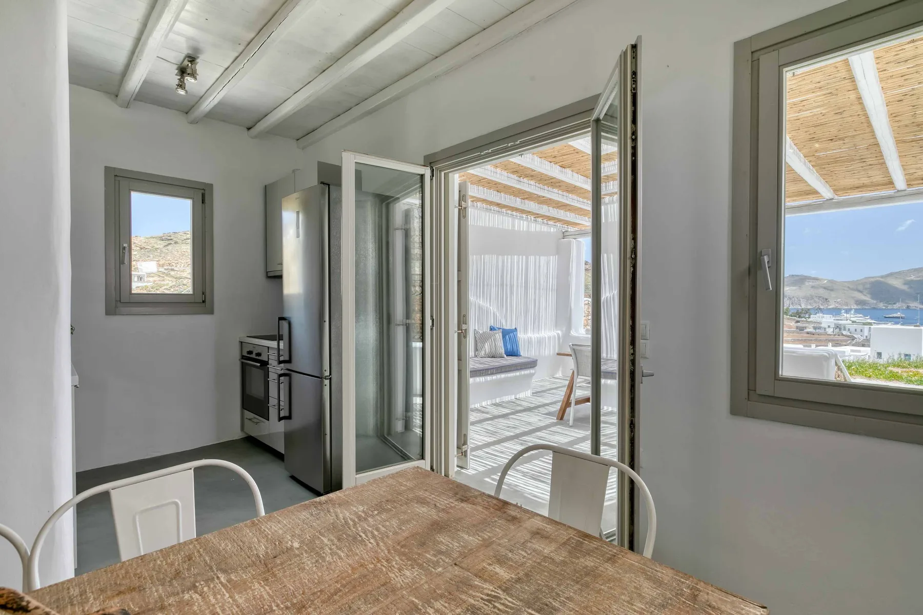 Comedor con una mesa de madera junto a puertas abiertas hacia un patio cubierto.