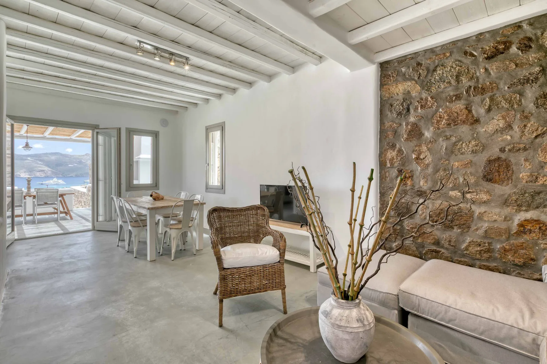 Una zona de estar y comedor con asientos junto a una pared de piedra.