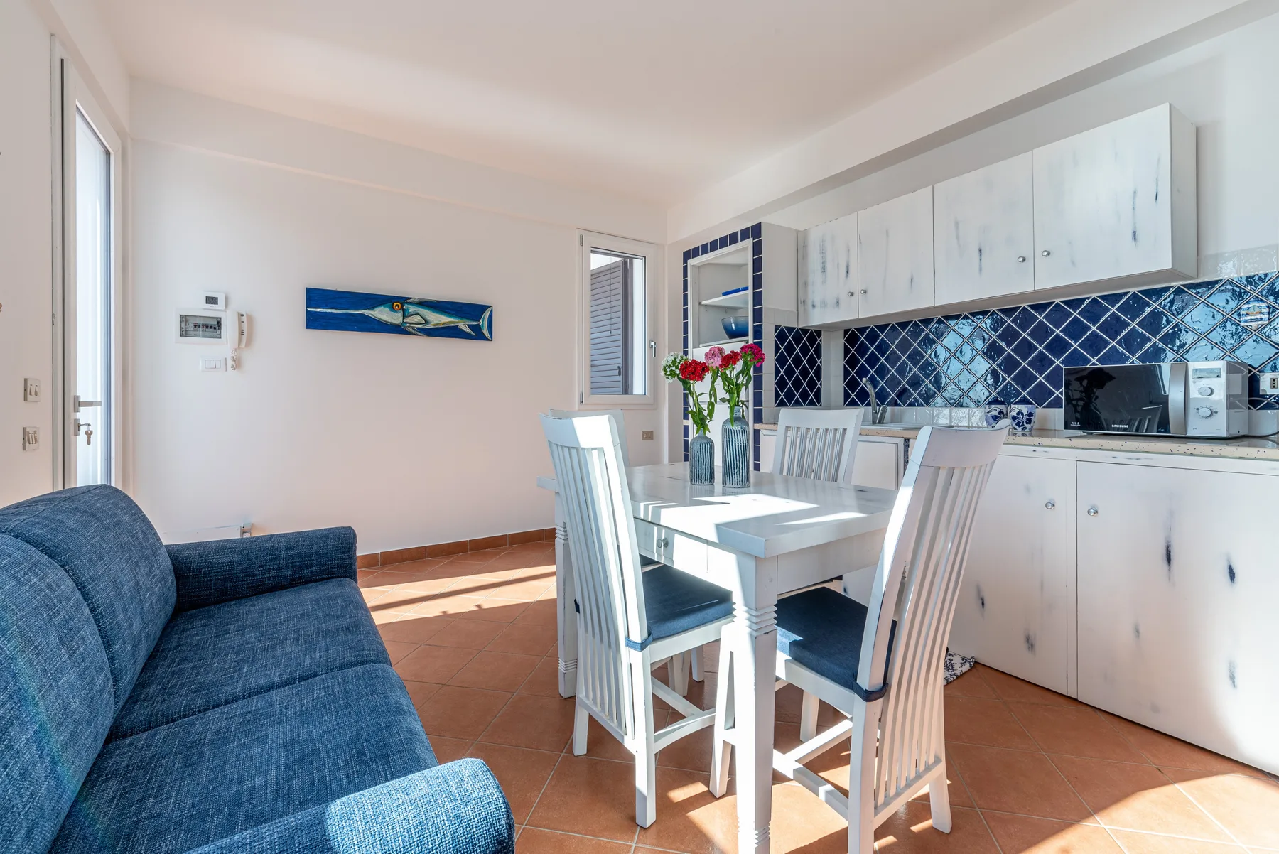 Un comedor luminoso con una mesa blanca junto a una cocina compacta.