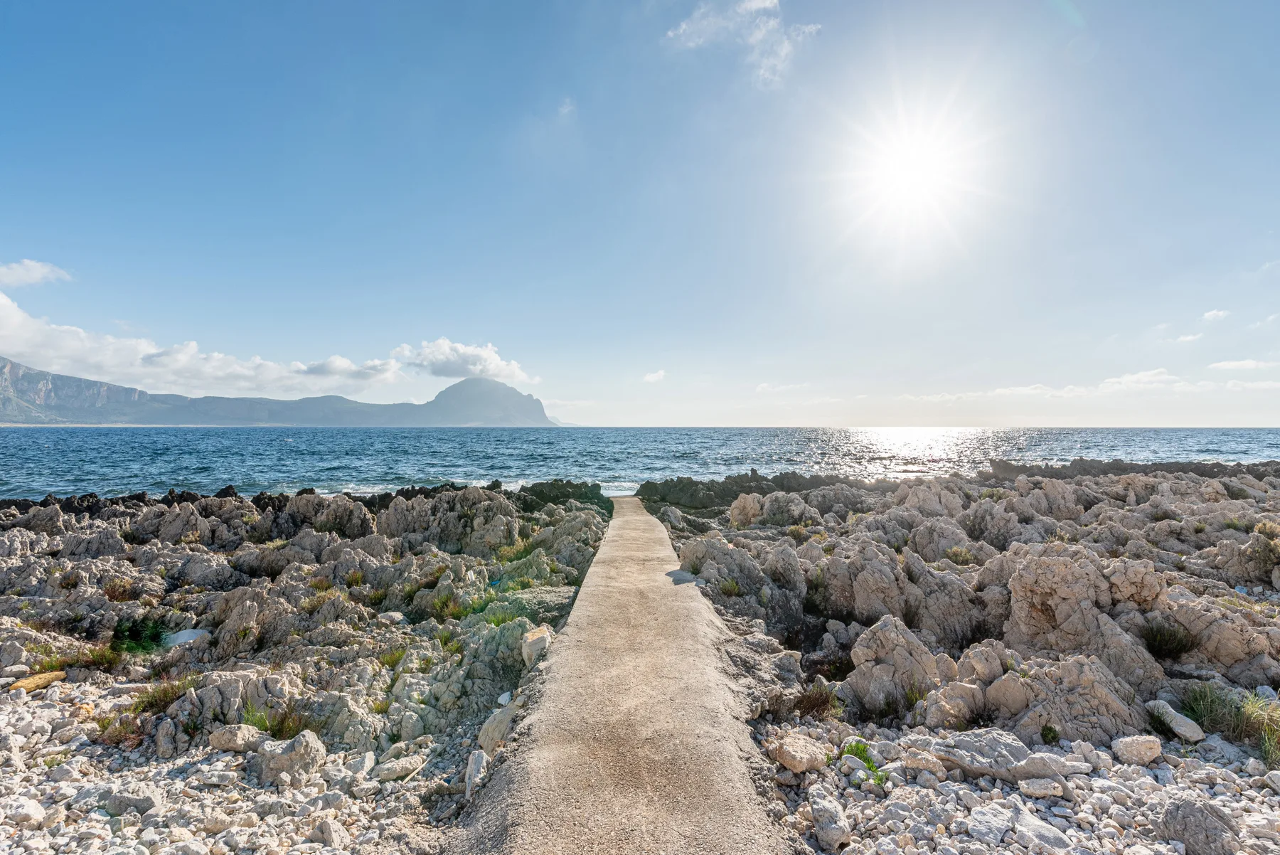 Un sendero estrecho atraviesa una costa rocosa hacia el mar.