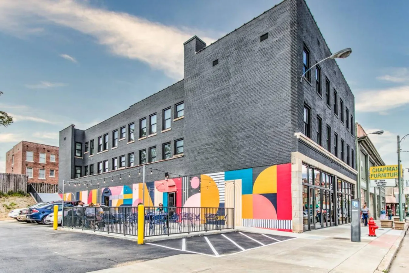 Un edificio moderno de ladrillo con murales coloridos en la fachada a nivel de calle.