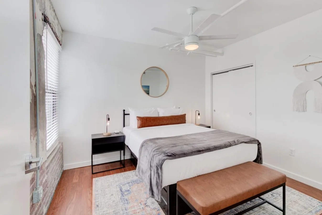 Un dormitorio luminoso con una cama, una mesita de noche y un ventilador de techo.