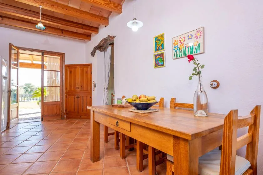 Un comedor con una mesa de madera, sillas y cuadros coloridos en la pared.