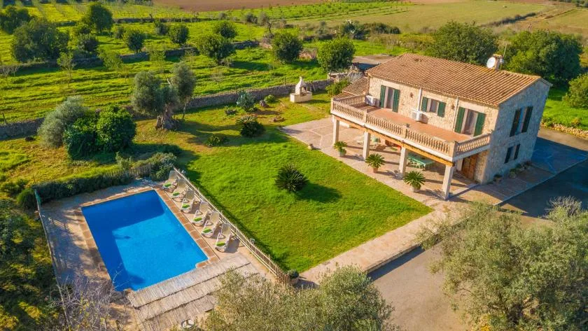 Una casa rural se encuentra junto a una piscina y jardines.