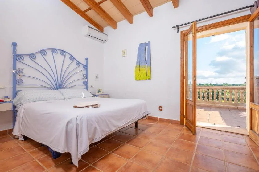 Un dormitorio con una cama junto a una puerta abierta que da a un balcón.