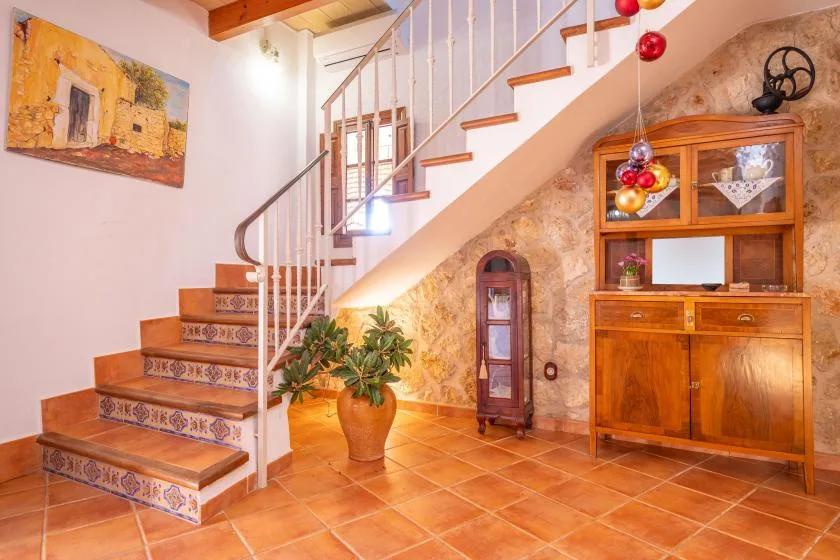 Un recibidor con suelo de baldosas, una escalera y un mueble de madera.
