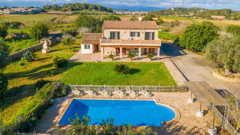 Una casa rural da a una piscina y a jardines cuidados.