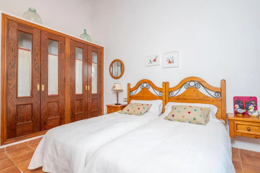 Un dormitorio con dos camas, armarios de madera y una pequeña mesita de noche.