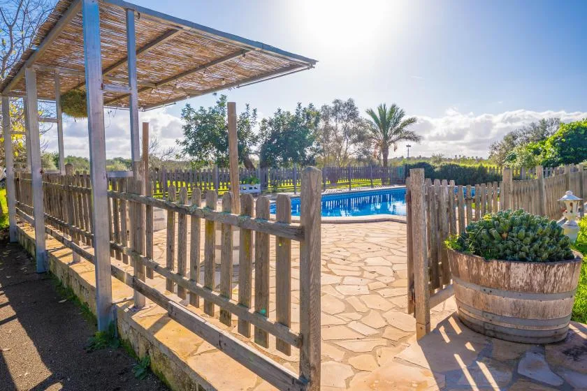Zona de piscina al aire libre con una pérgola de madera y patio pavimentado.