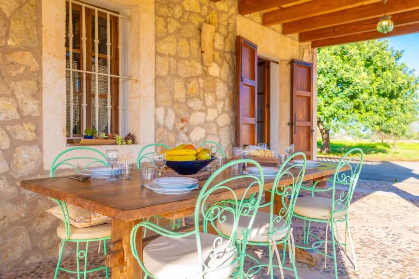 Un patio cubierto de piedra con una mesa de comedor y asientos metálicos verdes.