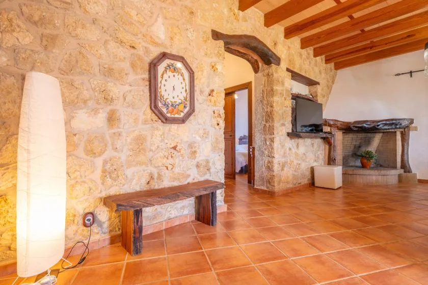 Una sala con paredes de piedra, un banco de madera y vigas expuestas.