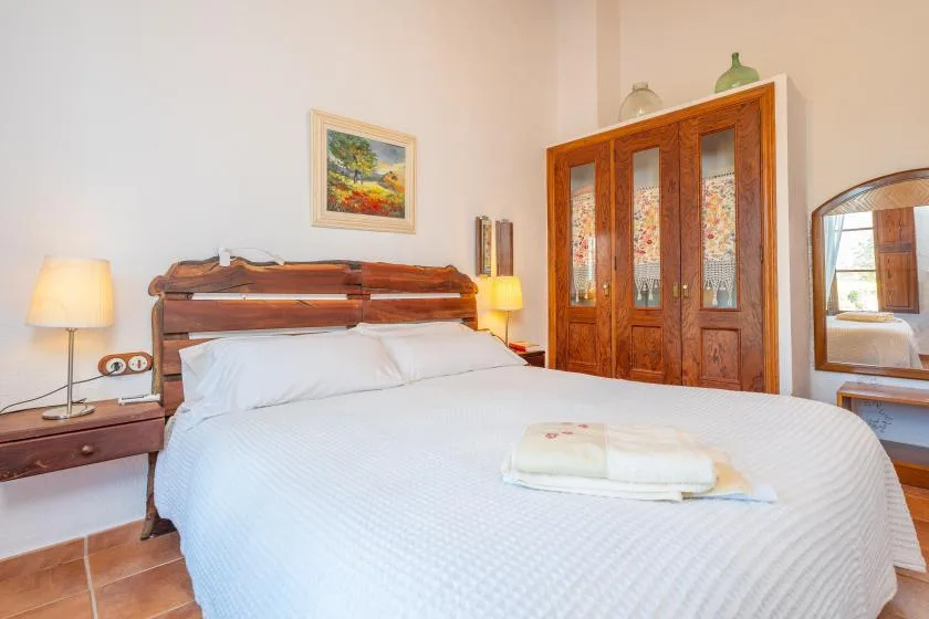 Un dormitorio con una cama de madera, ropa de cama blanca y un armario grande de madera.