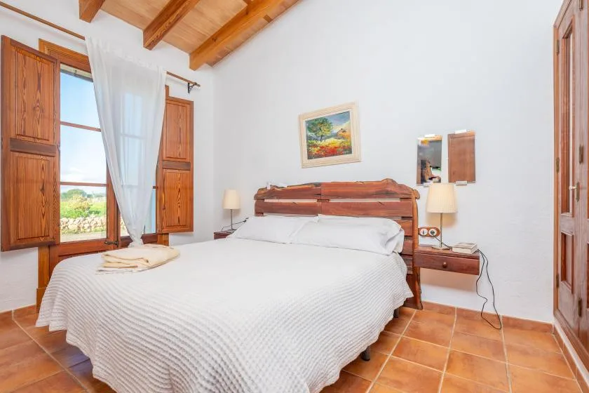 Un dormitorio con una cama grande, contraventanas de madera y vigas vistas en el techo.