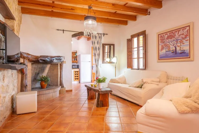 Una sala de estar con asientos claros, una chimenea y vigas de madera expuestas.