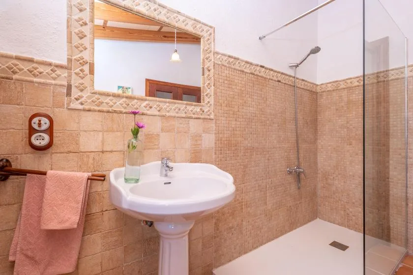 Un baño con azulejos, lavabo, espejo y ducha a ras de suelo.