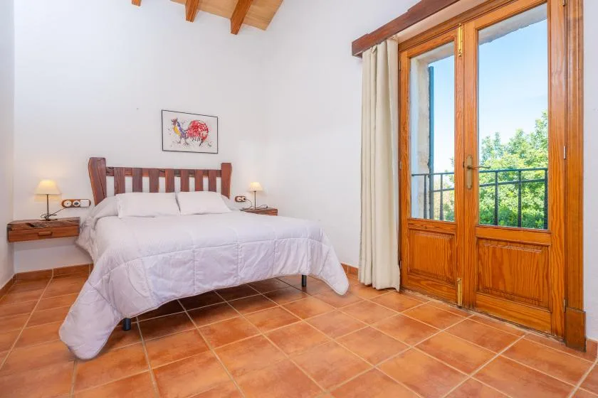 Un dormitorio con una cama junto a puertas de madera al balcón.