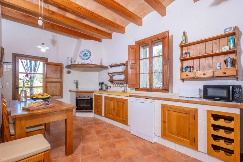 Una cocina amplia con muebles de madera, una mesa de comedor y vigas expuestas en el techo.