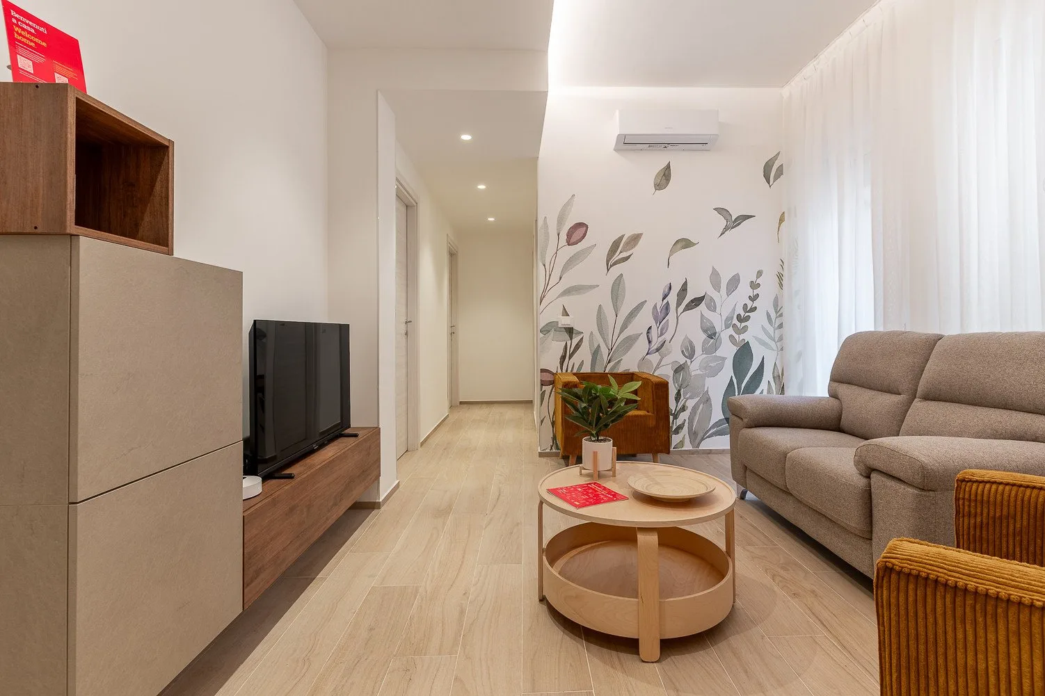 Una sala luminosa con sofá, televisor y mesa de centro redonda.