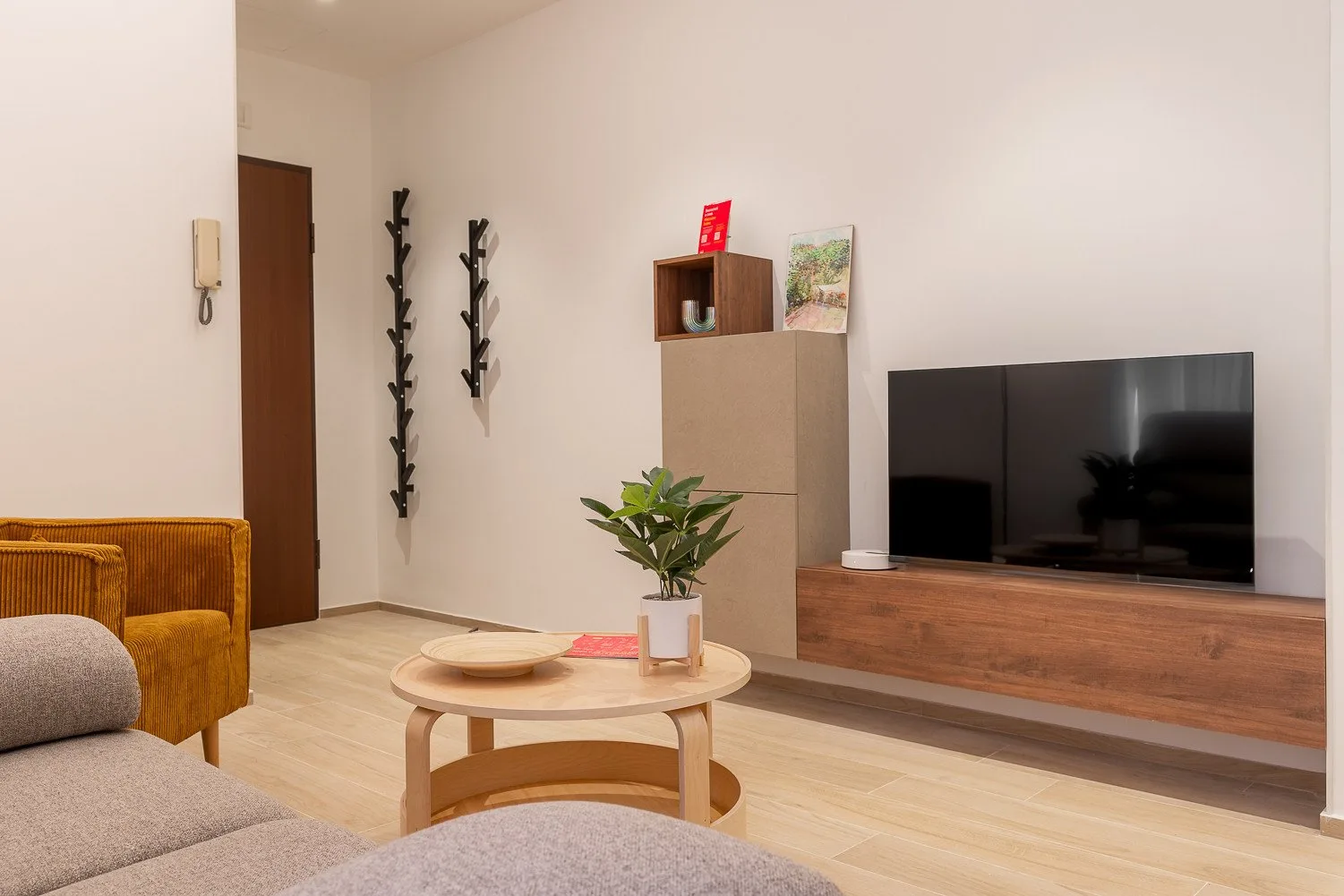 Una sala de estar con un televisor sobre un mueble de madera y asientos.