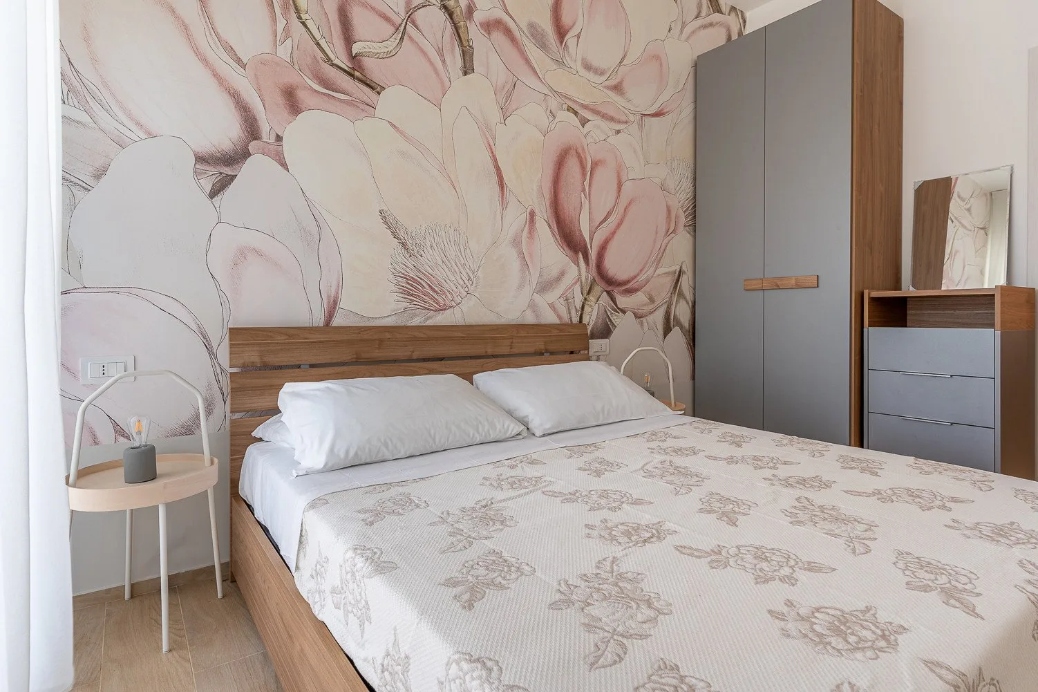 Un dormitorio con una cama grande y un mural floral en la pared detrás.