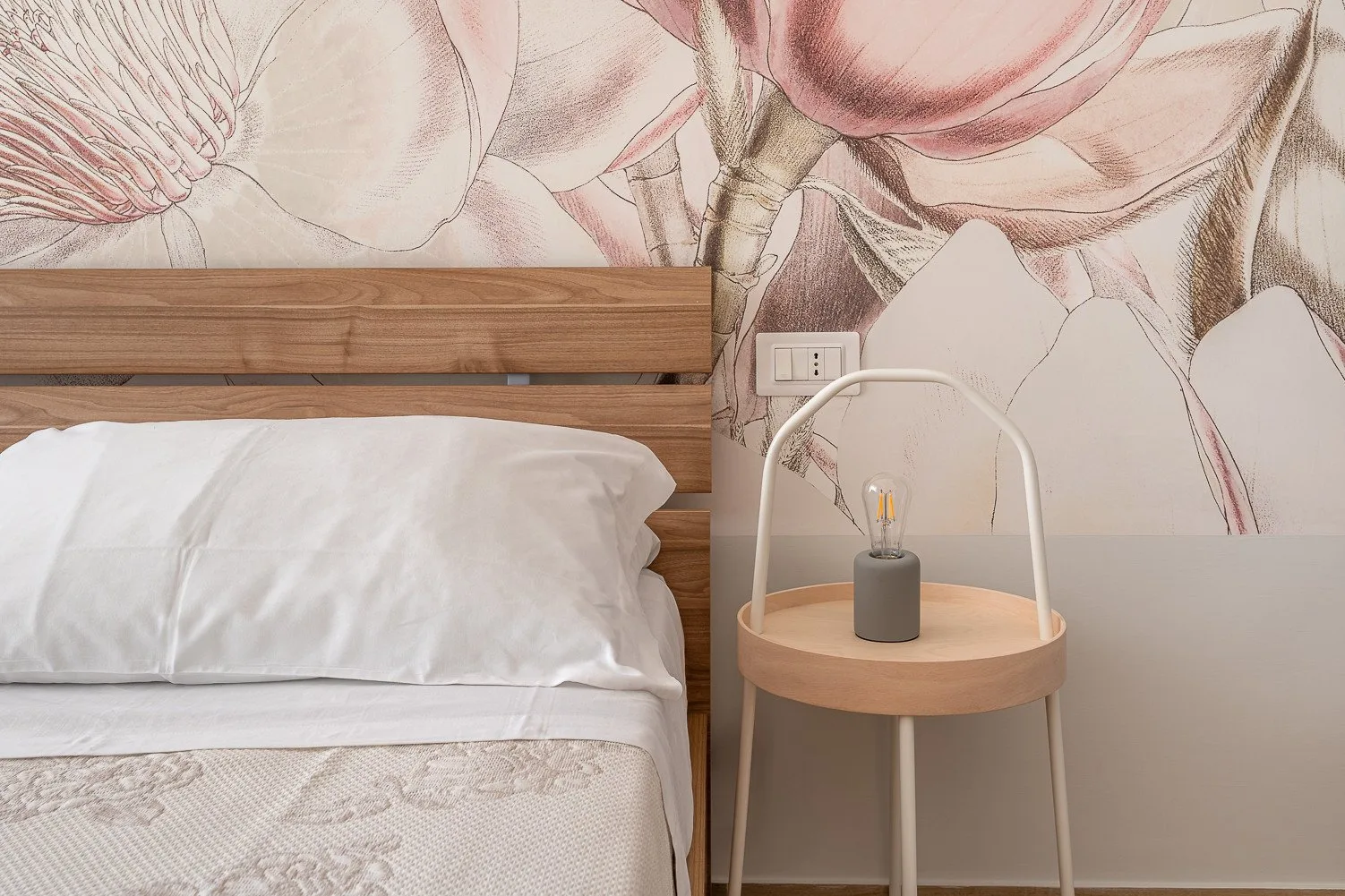 Un dormitorio con una cama de madera, ropa de cama blanca y una pequeña mesa de noche.