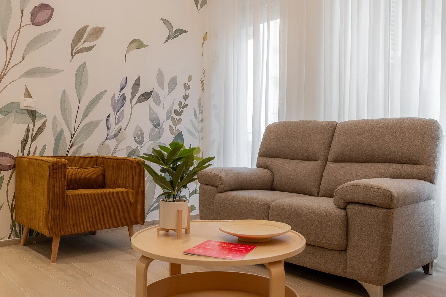 Una sala de estar con un sofá, un sillón y una mesa de centro redonda.