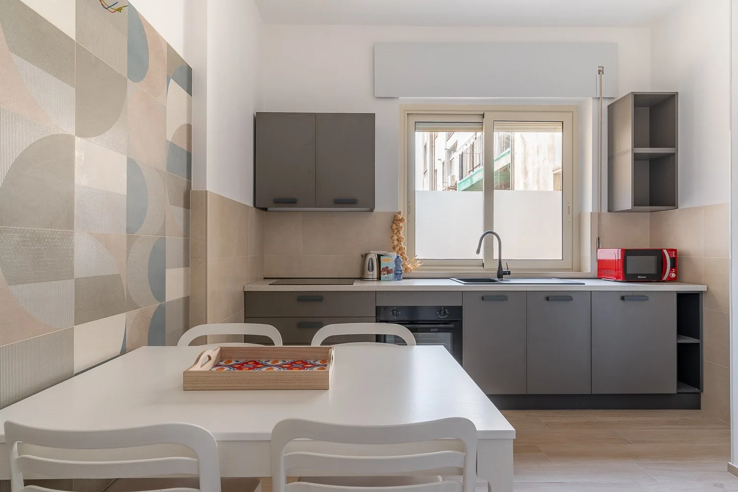 Una cocina luminosa con zona de comedor, mesa blanca y gabinetes grises.