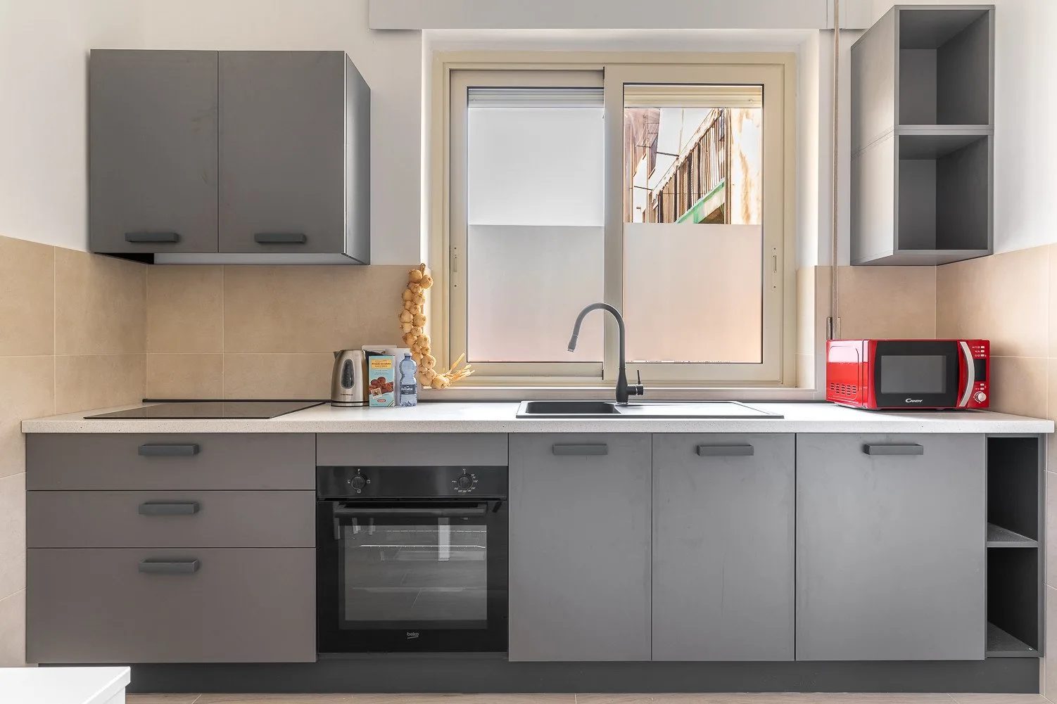 Una cocina moderna con gabinetes grises, un fregadero y una encimera.