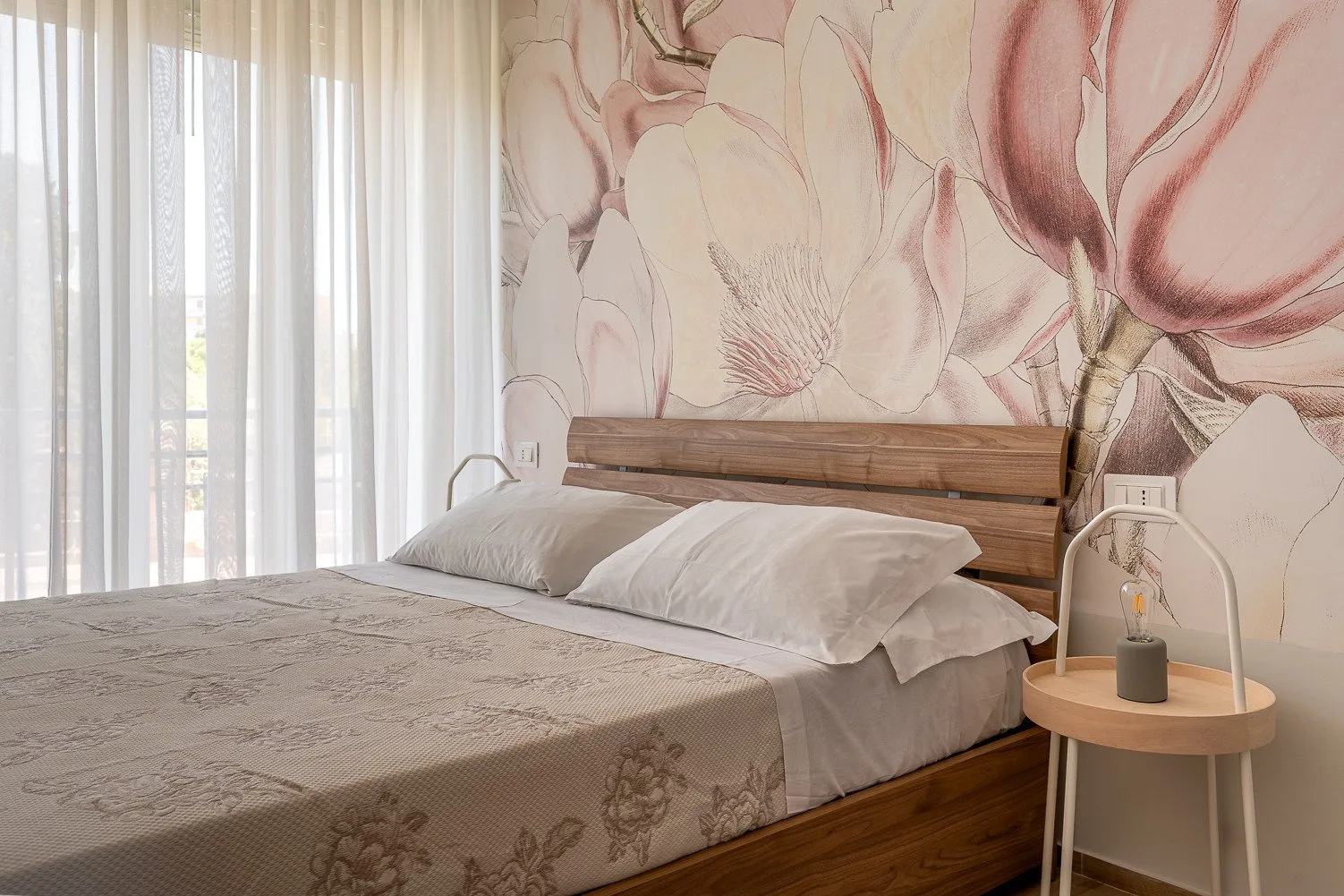 Un dormitorio con una cama bajo un gran mural floral.