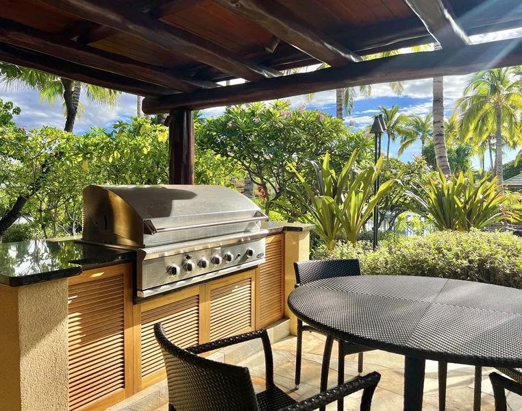 Un patio exterior cubierto cuenta con una parrilla empotrada y una mesa de comedor.