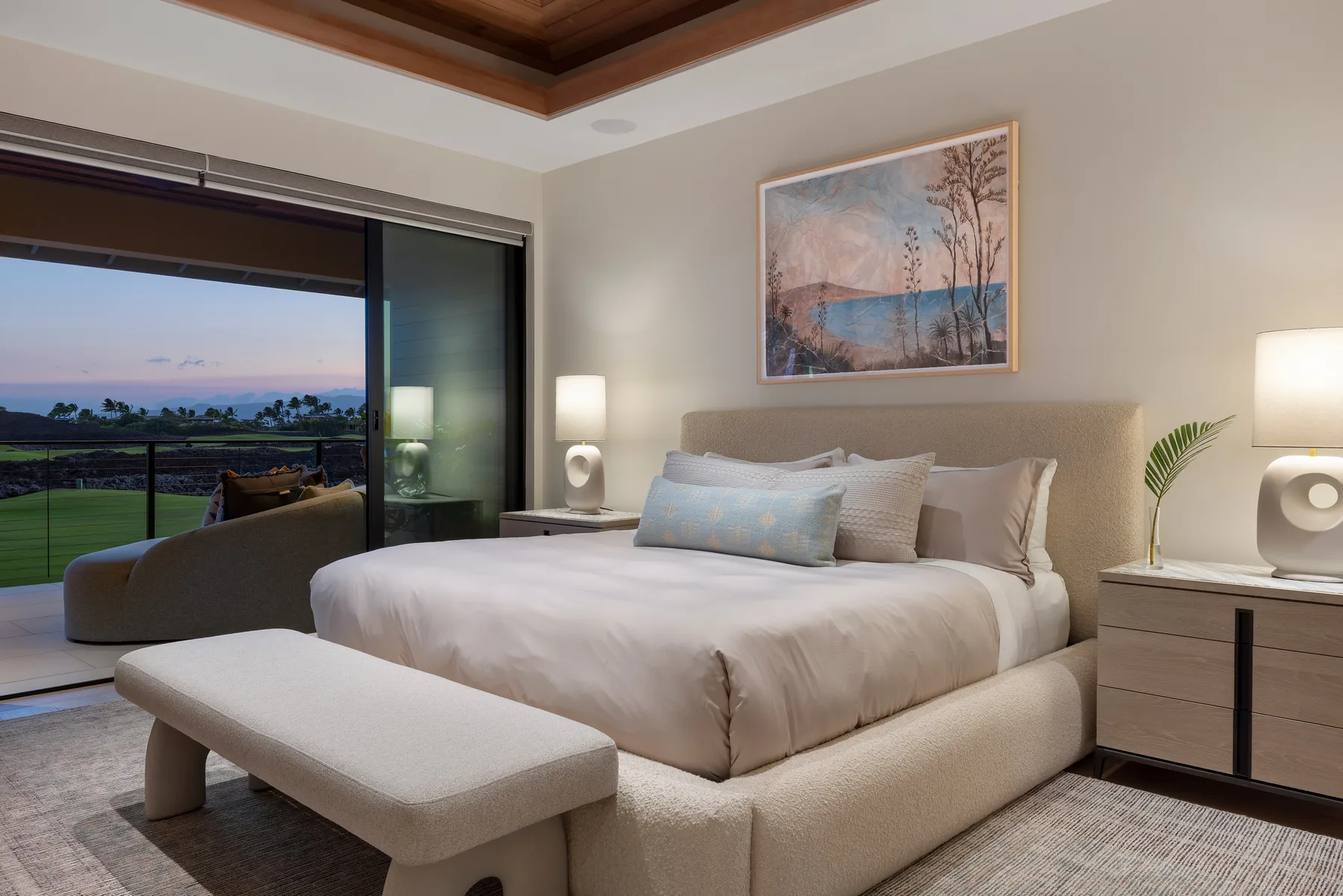 A bedroom with a neatly made bed and sliding glass doors overlooking a landscape.