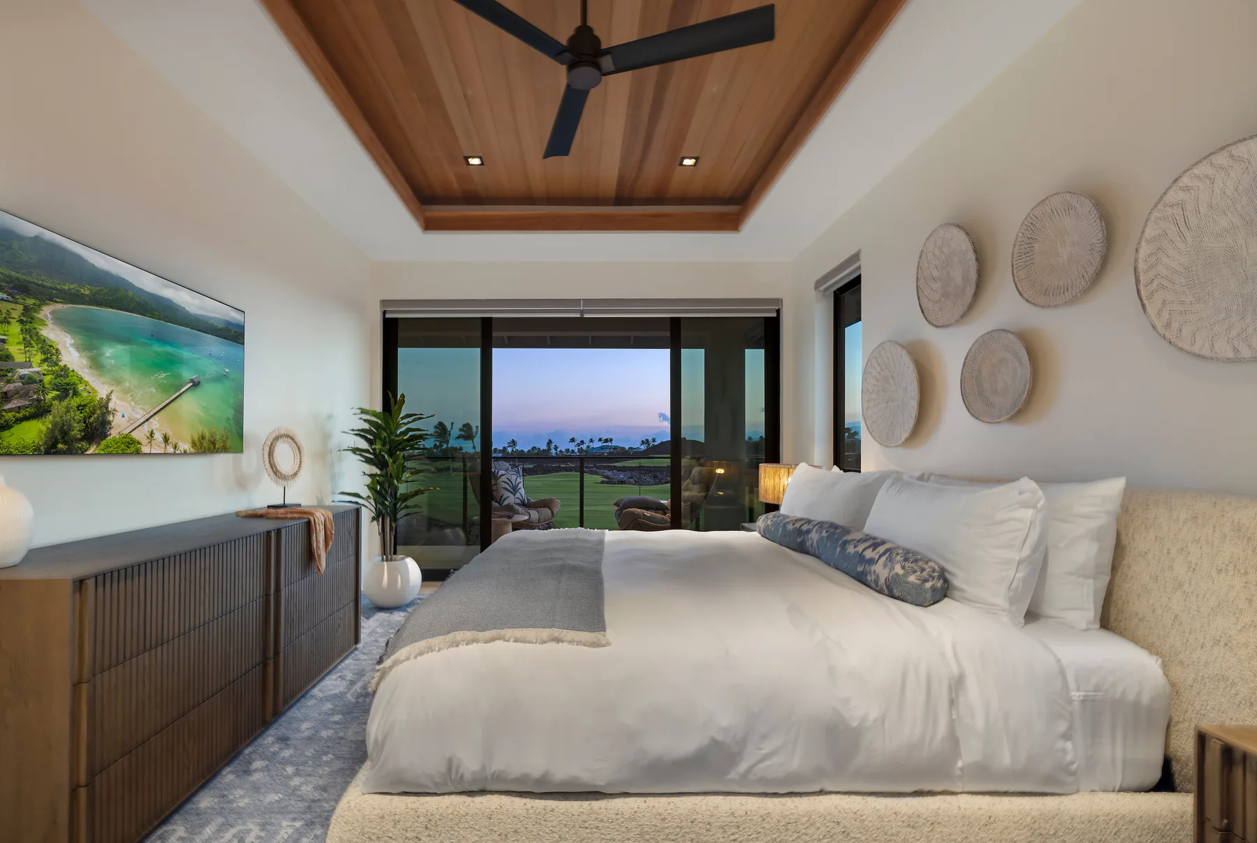Un dormitorio con una cama grande frente a puertas corredizas de vidrio y vistas al jardín.