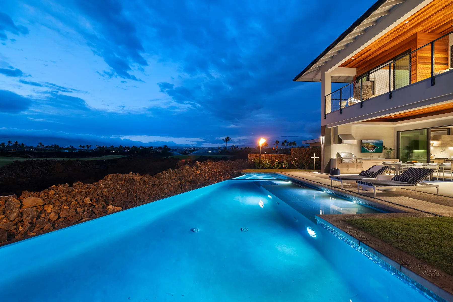 Una piscina al aire libre junto a una casa moderna al anochecer.