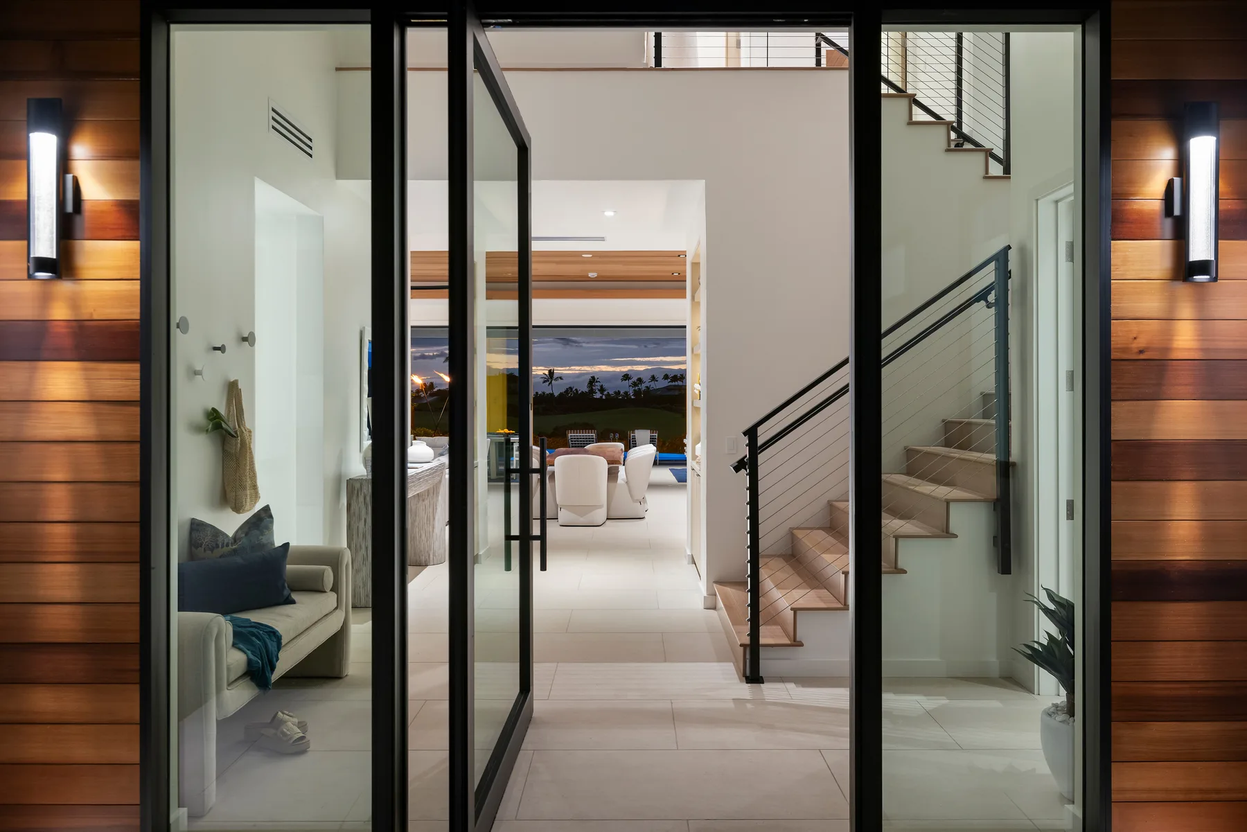Un pasillo interior moderno da a una sala de estar, con una escalera a un lado.
