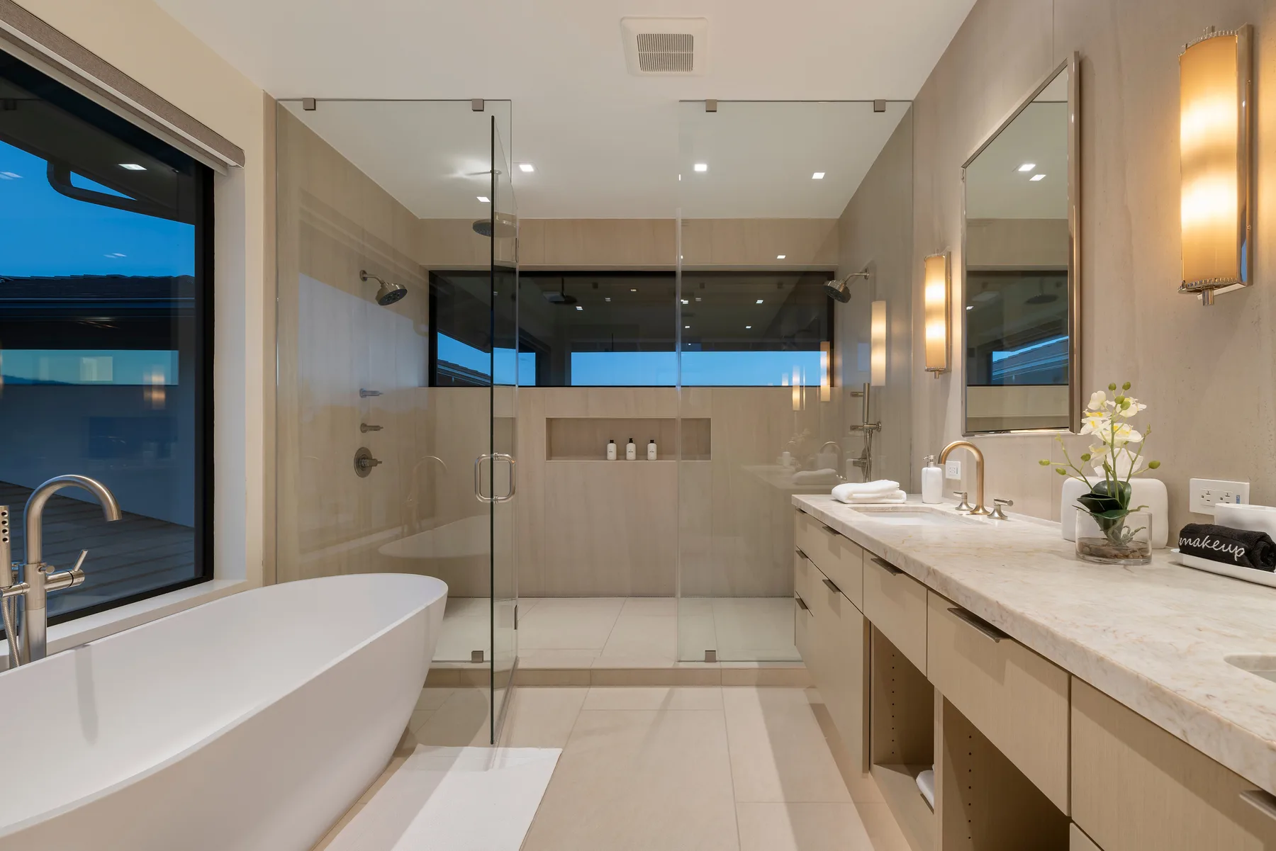 A spacious bathroom with a glass shower, freestanding tub, and long vanity.