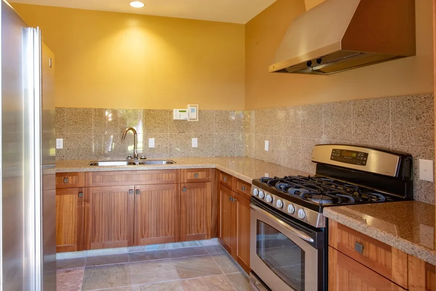 Una cocina de tonos cálidos con gabinetes de madera, fregadero y estufa.