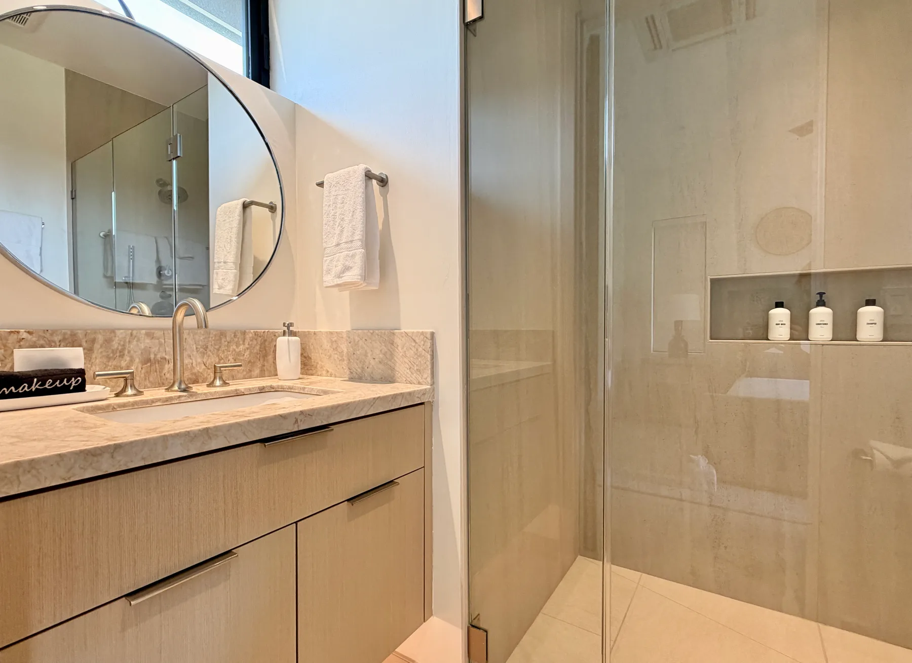 Un lavabo de baño junto a una ducha con mampara de vidrio.