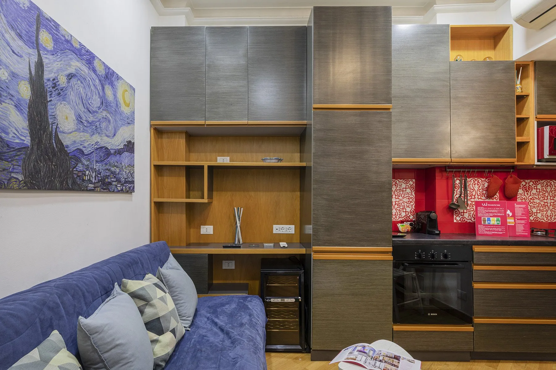 Una sala de estar con asientos azules, muebles de madera y un cuadro colorido.
