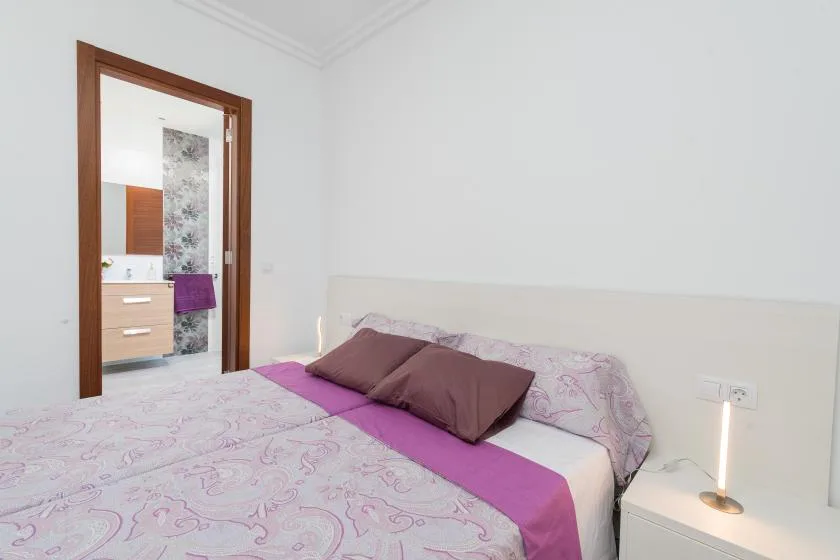 A bedroom with a bed and a bedside table beside an open doorway.
