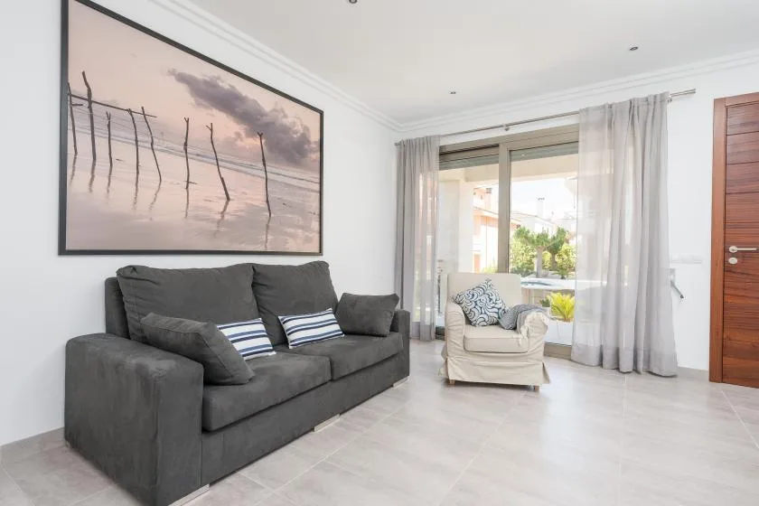 A bright living room with a dark sofa and a large window.